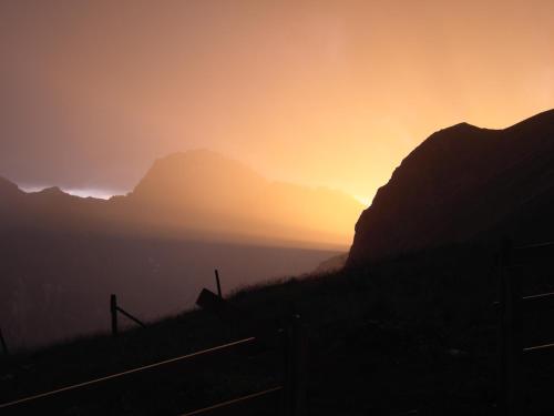 a sunset in the mountains with a fence in the foreground at Hotel Preda Kulm in Bergün
