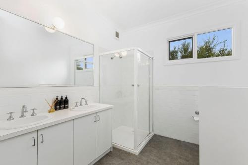a white bathroom with two sinks and a shower at Lochaber in Point Lonsdale