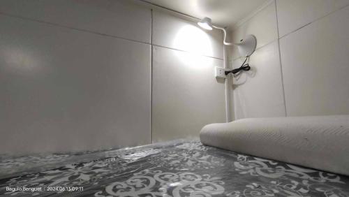 a room with a bed with a light on the wall at Kochimoto Guesthouse in Baguio