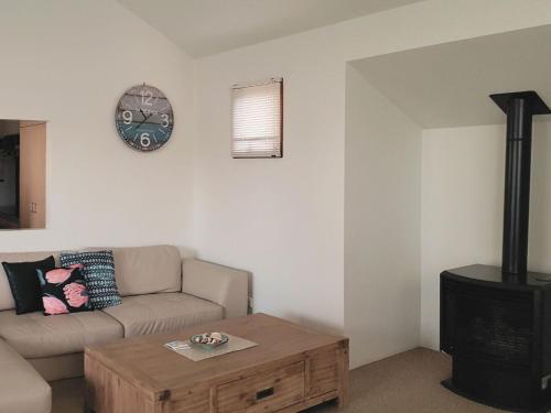 a living room with a couch and a clock on the wall at Lonsdale Shores in Point Lonsdale