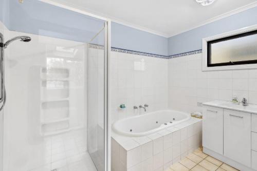 a white bathroom with a tub and a shower at Maison Cottage in Queenscliff