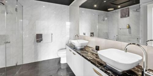 a white bathroom with a sink and a toilet at Penthouse Ozone in Queenscliff