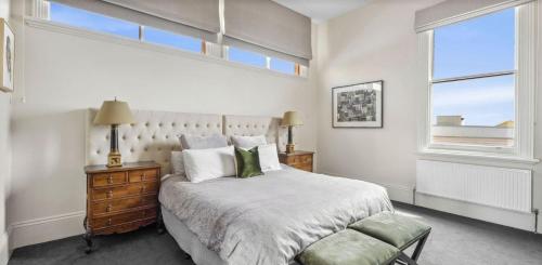 a white bedroom with a bed and a window at Penthouse Ozone in Queenscliff