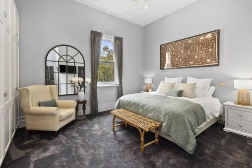 a bedroom with a bed and a chair at Pelicans at the Ozone in Queenscliff