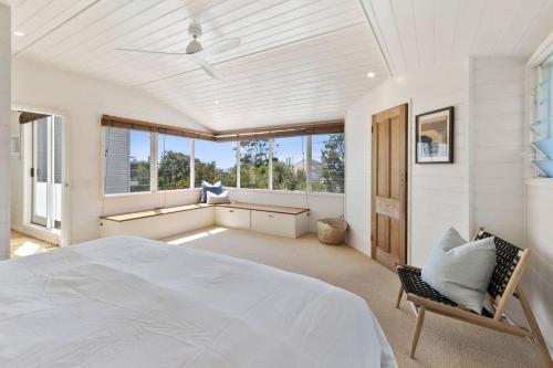 a white bedroom with a large bed and windows at Ripview in Point Lonsdale