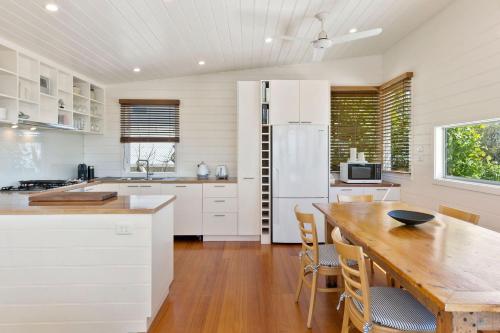 a kitchen with a wooden table and a white refrigerator at Ripview in Point Lonsdale