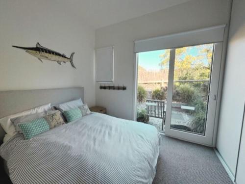 a bedroom with a bed and a large sliding glass door at Sand Dunes in Point Lonsdale