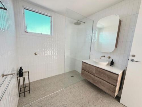 a white bathroom with a sink and a mirror at Sand Dunes in Point Lonsdale