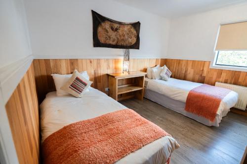 a bedroom with two beds and a window at Hotel Aquaterra in Puerto Natales