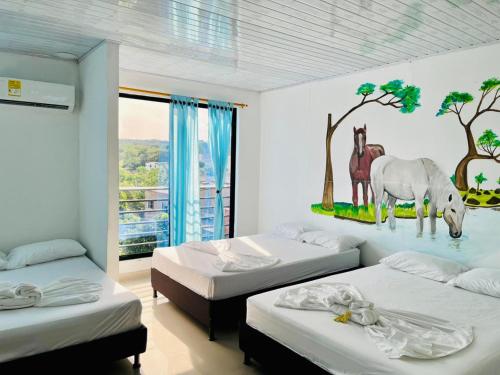 a room with three beds and a mural of a horse at Apartahotel Dazuwi in Doradal