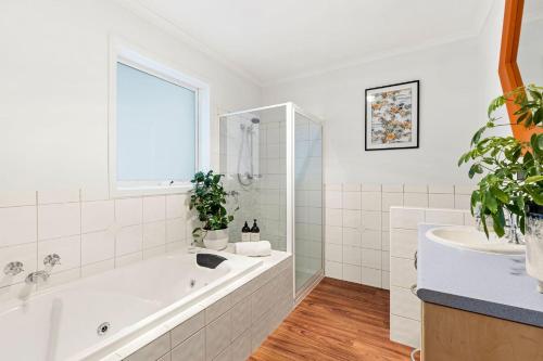 a white bathroom with a tub and a sink at The Springs in Point Lonsdale