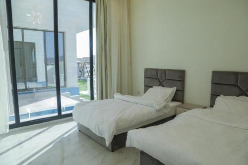 a bedroom with two beds and a large window at هلا شاليه اتين in Salalah
