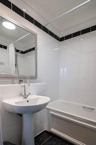 a bathroom with a sink and a tub and a mirror at Honest Lawyer Hotel in Durham