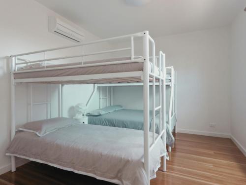 two bunk beds in a white room with wood floors at Taworri in Queenscliff