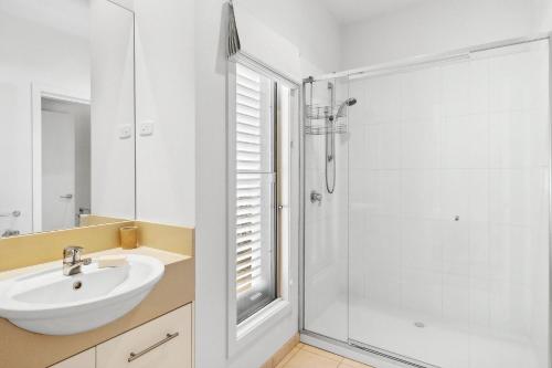 a white bathroom with a sink and a shower at Willos in Queenscliff