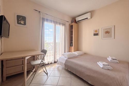 a bedroom with two beds and a desk and a window at Petra Afytos holiday in Afitos