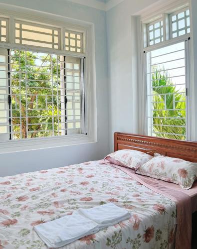 a bedroom with a bed with two windows at Vy Home in Thanh Ðông (1)