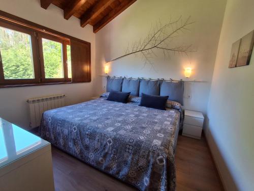 a bedroom with a bed with blue sheets and a window at El Cuadron in Camango