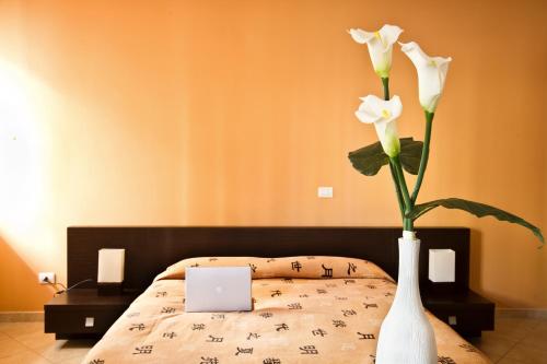 a white vase with two white flowers in a bedroom at Marisal Accommodation in Alghero