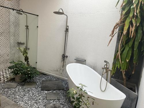 a bathroom with a bath tub and a plant at Perolas Homestay in Xóm Chum Găng