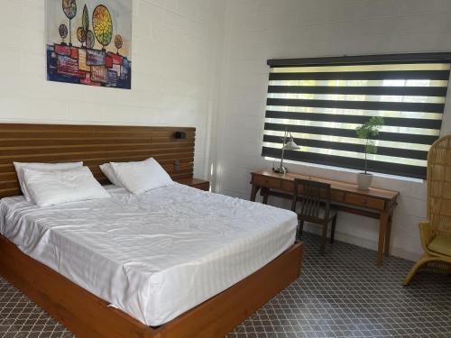 a bedroom with a bed and a desk and a window at Perolas Homestay in Xóm Chum Găng