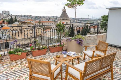 a patio with chairs and tables and a view of the city at El Khan Guesthouse & Art - A Complex of 4 Middle Eastern-Style Suites in Nazareth