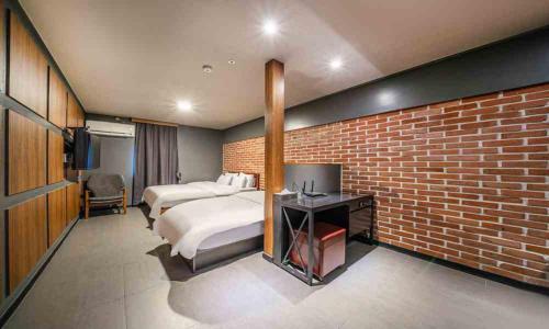 a bedroom with two beds and a brick wall at HOTEL STAY AYANA DAEJEON in Daejeon