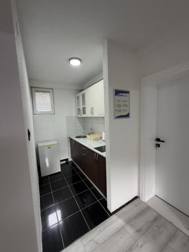 a kitchen with white cabinets and a black tile floor at Aqua apartment in Gornji Ribnik