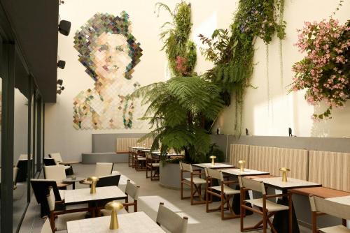 ein Restaurant mit Tischen und Stühlen und einem Gemälde an der Wand in der Unterkunft The Cloud One Lisbon in Lissabon