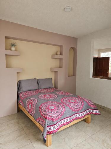 a bedroom with a large bed with a red blanket at CABAÑAS SANAMBO fraccionamiento los gallos in Balastre Rojo