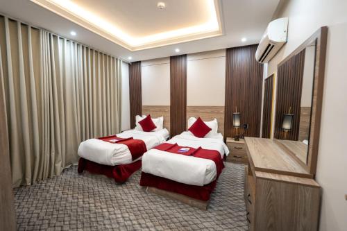 a hotel room with two beds and a mirror at راحتي هنا للشقق المخدومة 7 in Riyadh