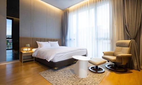 a bedroom with a bed and a chair and a window at Jeonju Tourist Hotel kkotsim in Jeonju