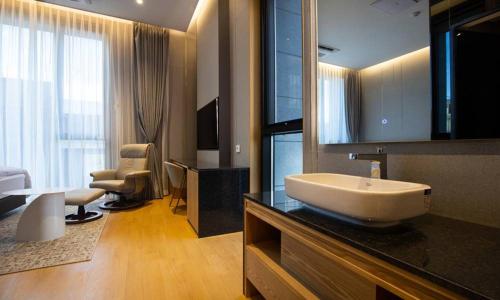 a bathroom with a sink and a living room at Jeonju Tourist Hotel kkotsim in Jeonju