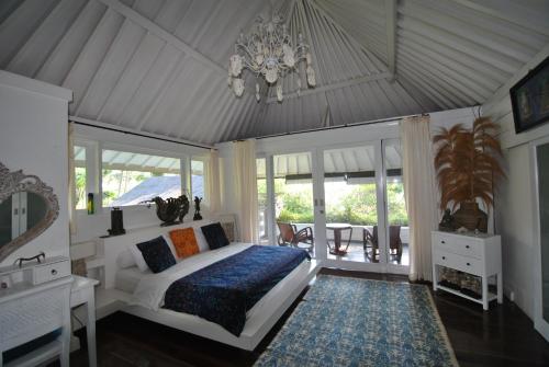 a bedroom with a bed and a chandelier at Villa Pantai Matanai in Tianyar