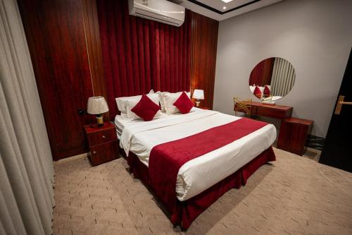 a bedroom with a large bed with red sheets at راحتي هنا للشقق المخدومة in Riyadh