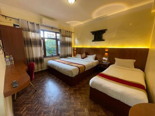 a hotel room with two beds and a desk at Hotel Atlantic in Kathmandu
