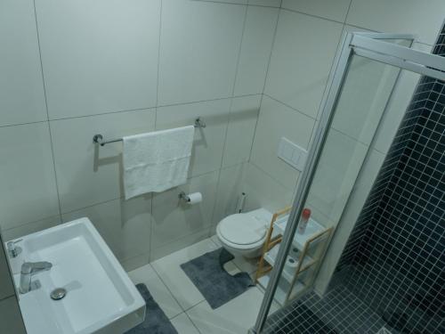 a white bathroom with a toilet and a sink at 77 ON Independence Avenue in Windhoek