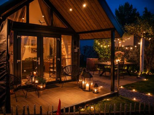 an outdoor deck with candles and a table with chairs at Tiny Haus Auszeit am See in Lathum