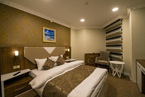 カルスにあるKars-i Si̇ri̇n Otelの大きなベッドと椅子が備わるホテルルームです。