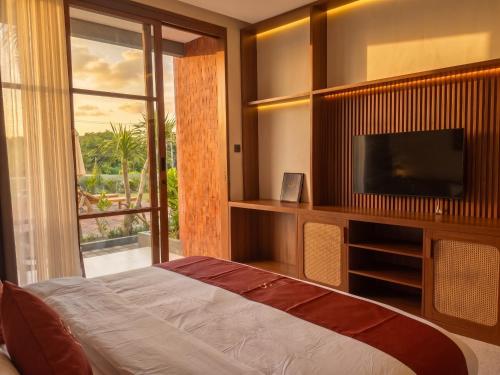 a bedroom with a bed and a tv and a window at Frontera Nyanyi in Tabanan