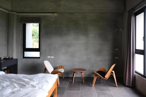 a bedroom with two chairs and a bed and a table at Tao Ye BnB in Miaoli