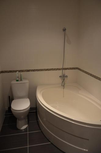 a bathroom with a white tub and a toilet at Apartments Ozo Park in Vilnius