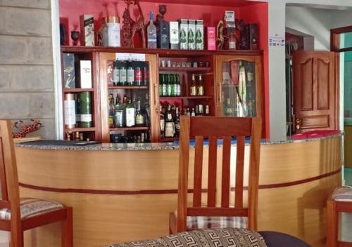 a bar with two chairs and a counter with alcohol at Tommy's Lounge Apartments in Nairobi