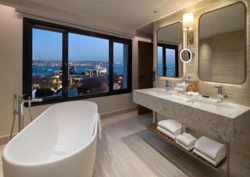 a bathroom with a large tub and a large window at Doubletree By Hilton Istanbul Macka in Istanbul
