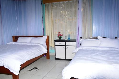 a bedroom with two beds and a window at Tommy's Lounge Apartments in Nairobi