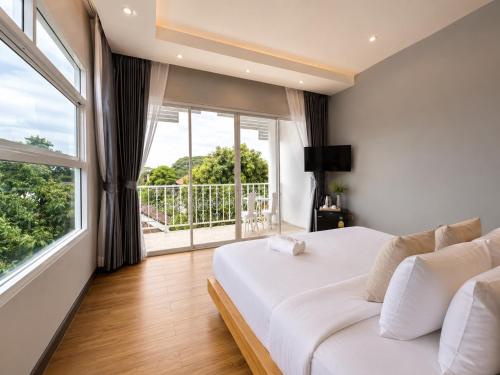 a bedroom with a white bed and a large window at The White House Rachamankha - Adults Only in Chiang Mai