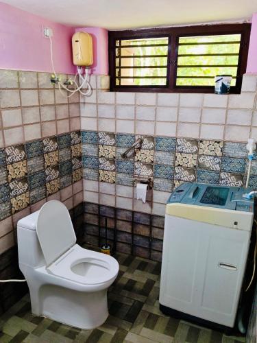 a bathroom with a toilet and a phone on the wall at Cherys Bunglow Homestay- Rooms in Thiruvalla