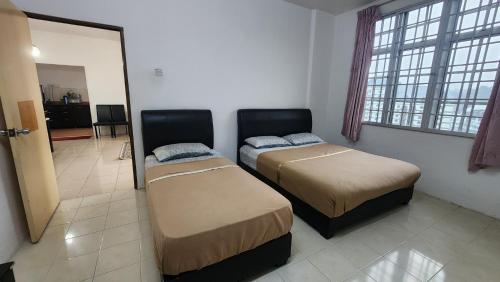 two beds sitting in a room with a mirror at Merlin Home@Crown Imperial Court in Tanah Rata