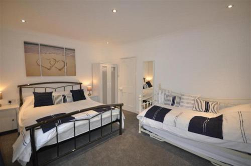 two beds in a bedroom with white and black at Ocean House - Weymouth in Weymouth