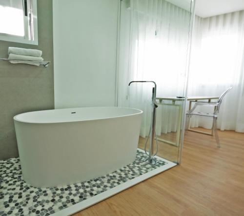 a white bath tub in a bathroom with a table at Hotel Vila da Guarda in A Guarda